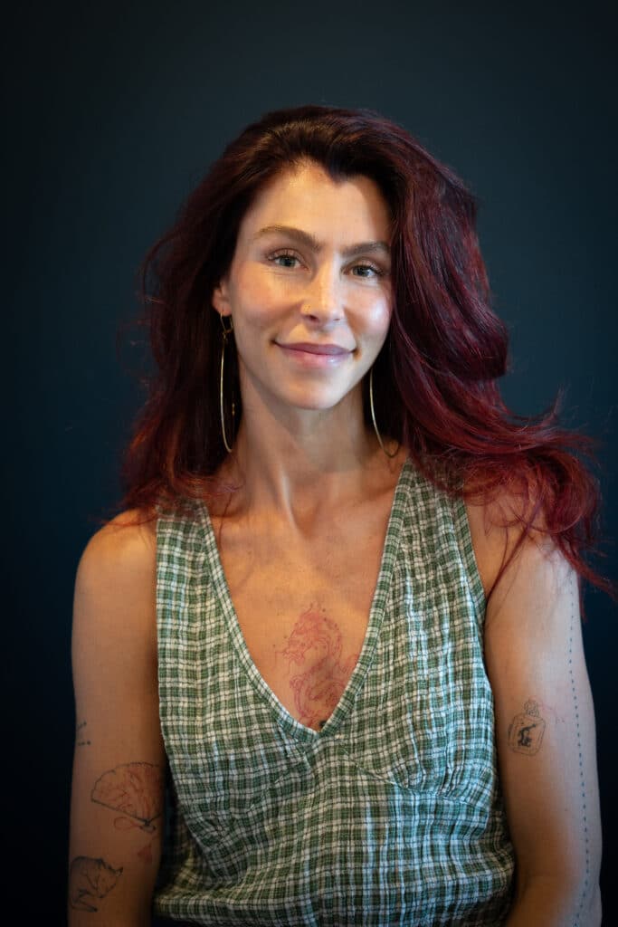 a woman with red hair smiles at the camera