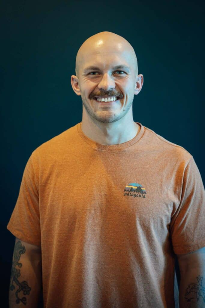 A man in an orange shirt smiles at the camera