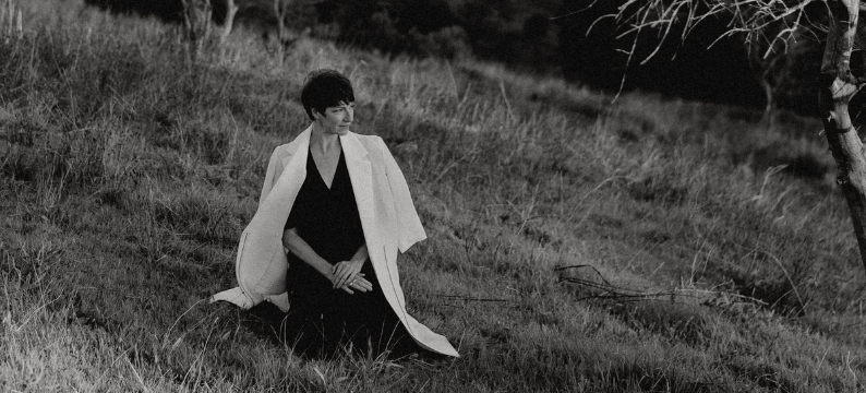 a woman sits on a hillside in meditation