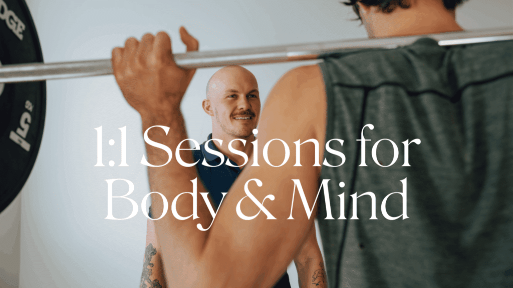 a personal trainer smiles at a client lifting a barbell